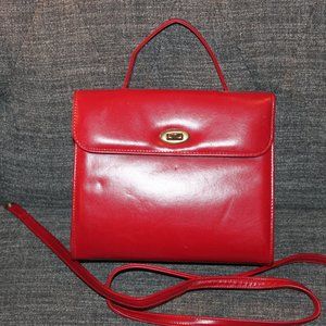 Red pocketbook which can be carried by hand or by using the shoulder strap.
